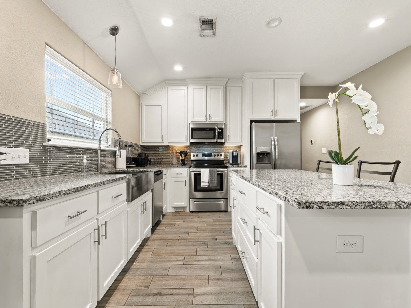 White kitchen with granite island and stainless appliances