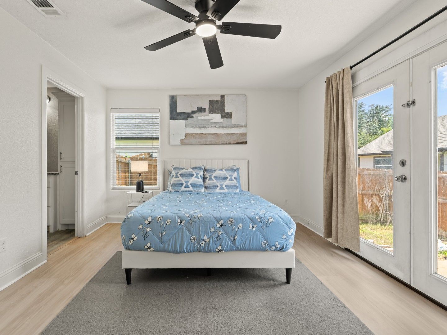Furnished bedroom with queen bed and patio doors